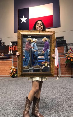 Maya Poduval holding her painting at the rodeo. Photo courtesy of the Klein Cain Art Twitter Page, @KleinCainArt.