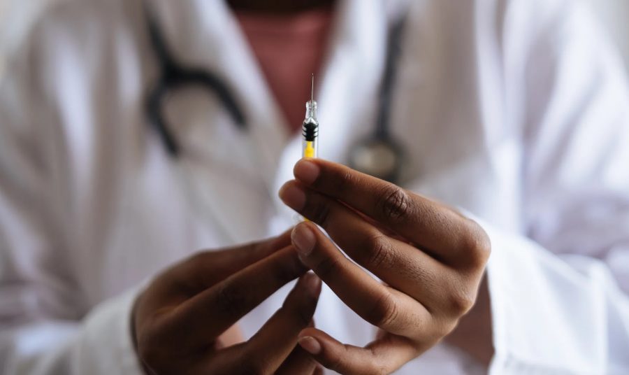 Doctor holds vaccine as they prepare to administer. Wikimedia commons author Retha Ferguson